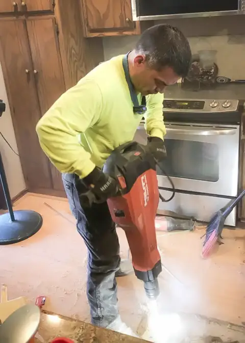 A Lieber Mechanical technician works on the floor inside a customer's kitchen.